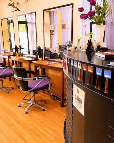 Meja kasir dan resepsionis Claffa Salon dengan deretan sampel warna rambut untuk konsultasi pewarnaan serta area styling di latar belakang